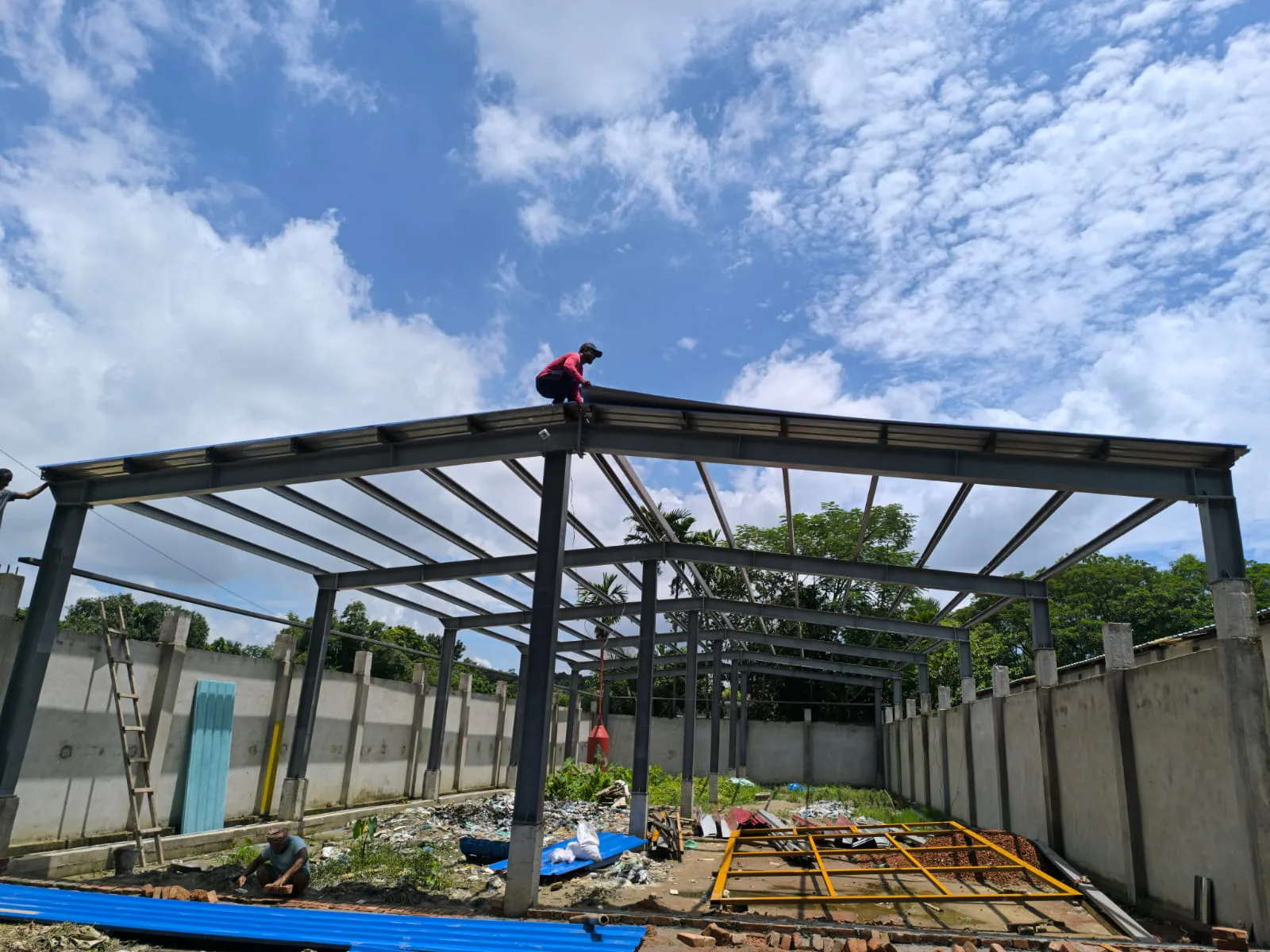 Worker installing roof cladding on a steel building frame